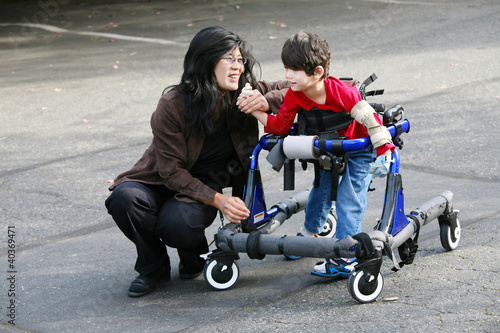 Mother with disabled son walking outdoors with walker
