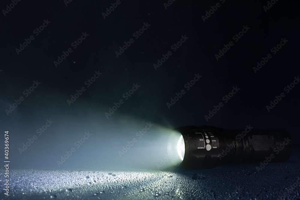 Obraz premium Tactical waterproof flashlight with waterdrops and smoke