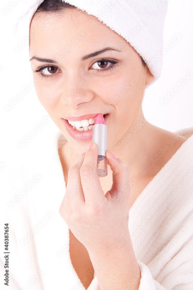 Young woman applying lipstick with a bath robe Young woman applying lipstick with a bath robe