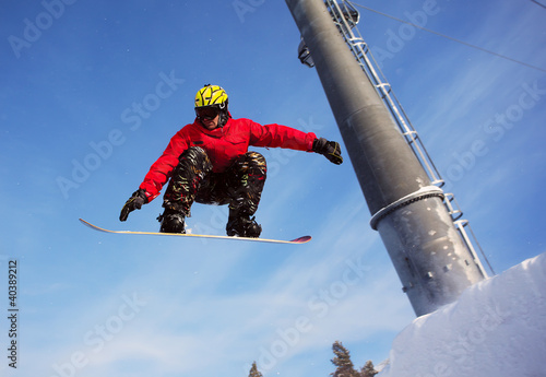 Snowboarder jumping through air with  blue sky in background photo