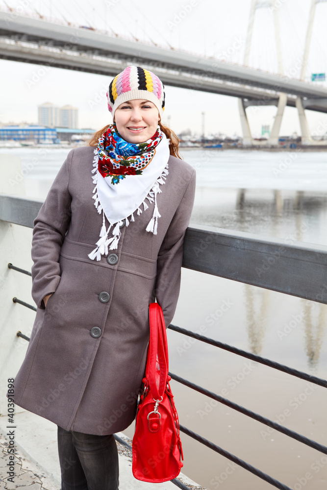 Obraz premium Portrait of happy young female with red bag on embankment