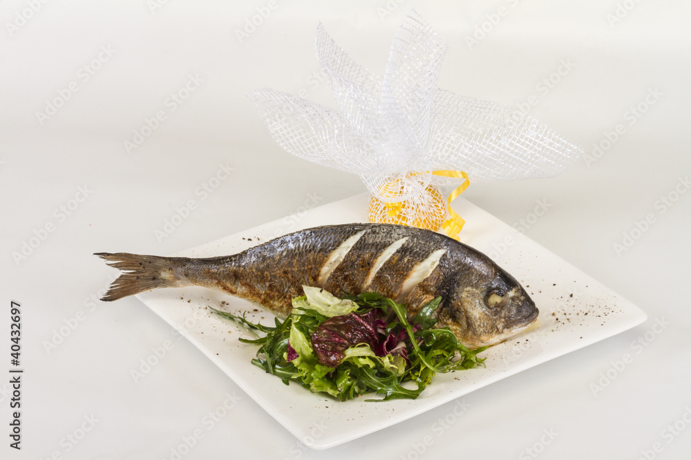 Dorada fish with salad on the white plate. Studio shot Dorada fish with salad on the white plate. Studio shot