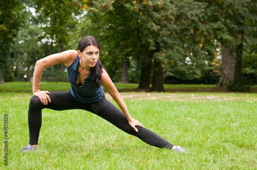 Woman performs stretching before sport in park