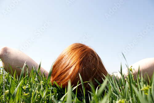 фотографія Red haired woman laying in grass looking up
