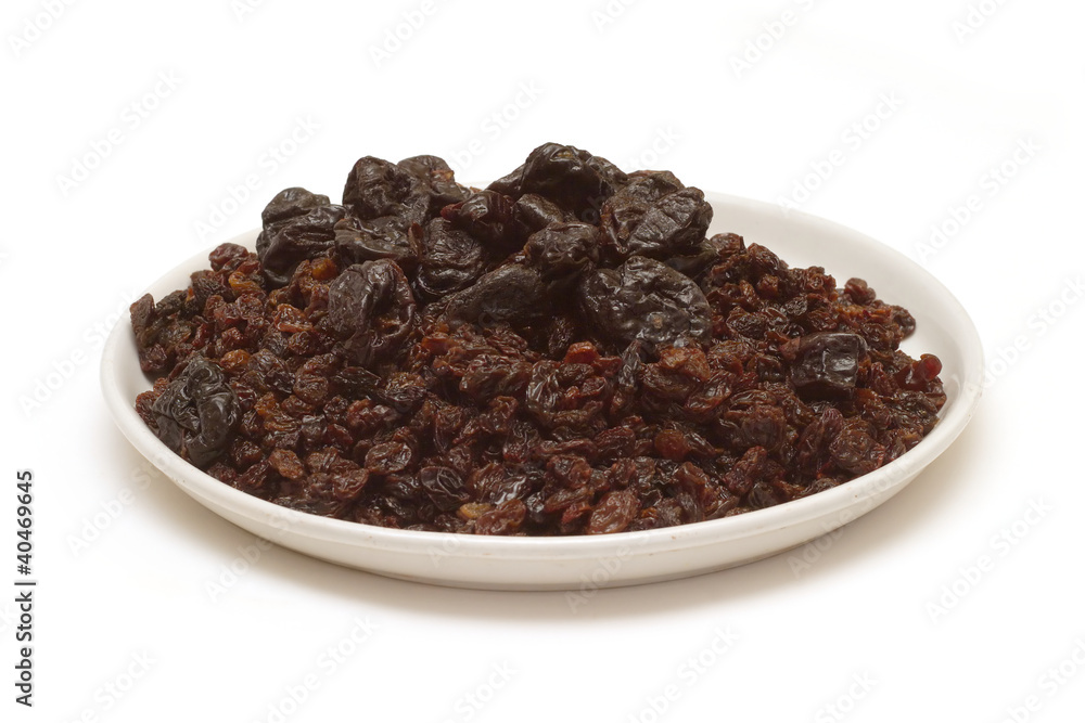 Lot of prunes, raisins on round plate isolated on white Lot of prunes, raisins on round plate isolated on white