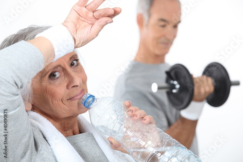 Elderly woman drinking water after gym session