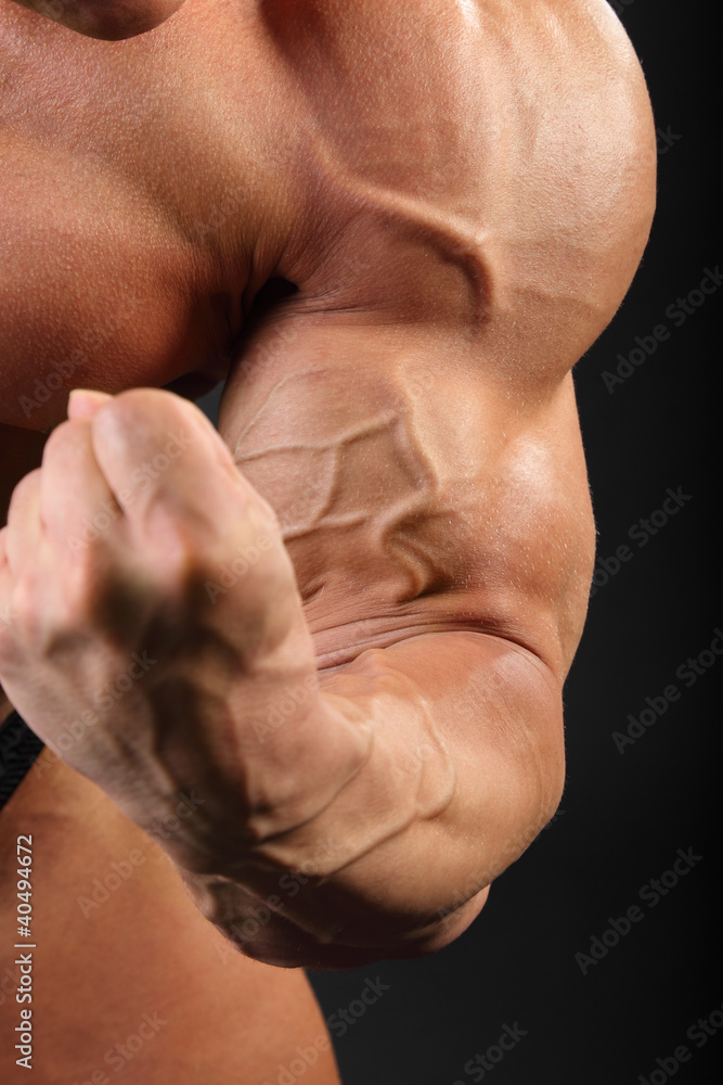 Undressed sunburnt bodybuilder demonstrates biceps