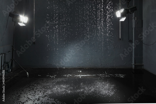 Rain in studio with black walls, lighting system