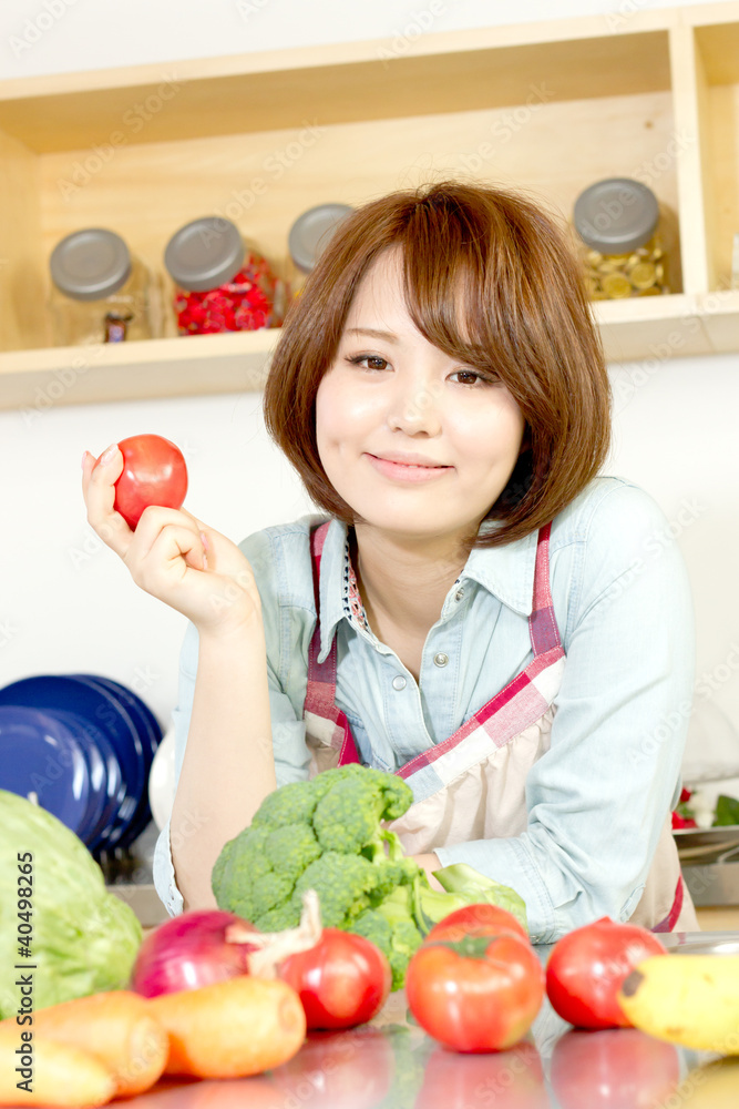 Beautiful young woman in kitchen making salad. Portrait of asian