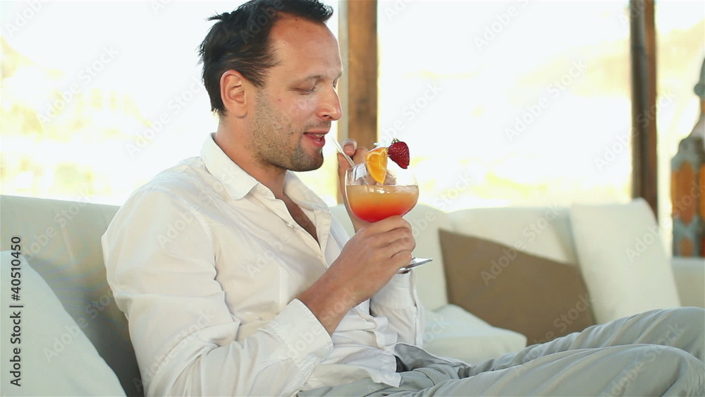 Happy young man drinking exotic cocktail in lounge bar Happy young man drinking exotic cocktail in lounge bar