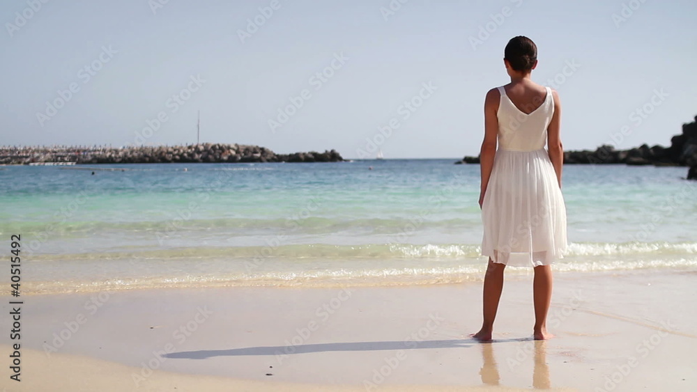 Woman in white dress standing on beautiful tropical beach Woman in white dress standing on beautiful tropical beach