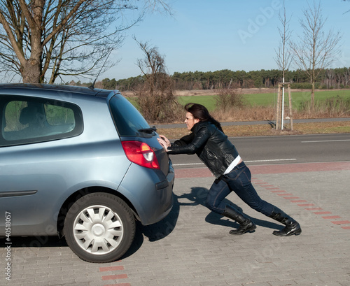 junge frau schiebt ihr auto