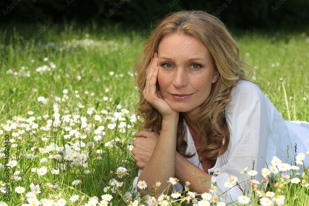 Woman laying down in field full of flowers Woman laying down in field full of flowers