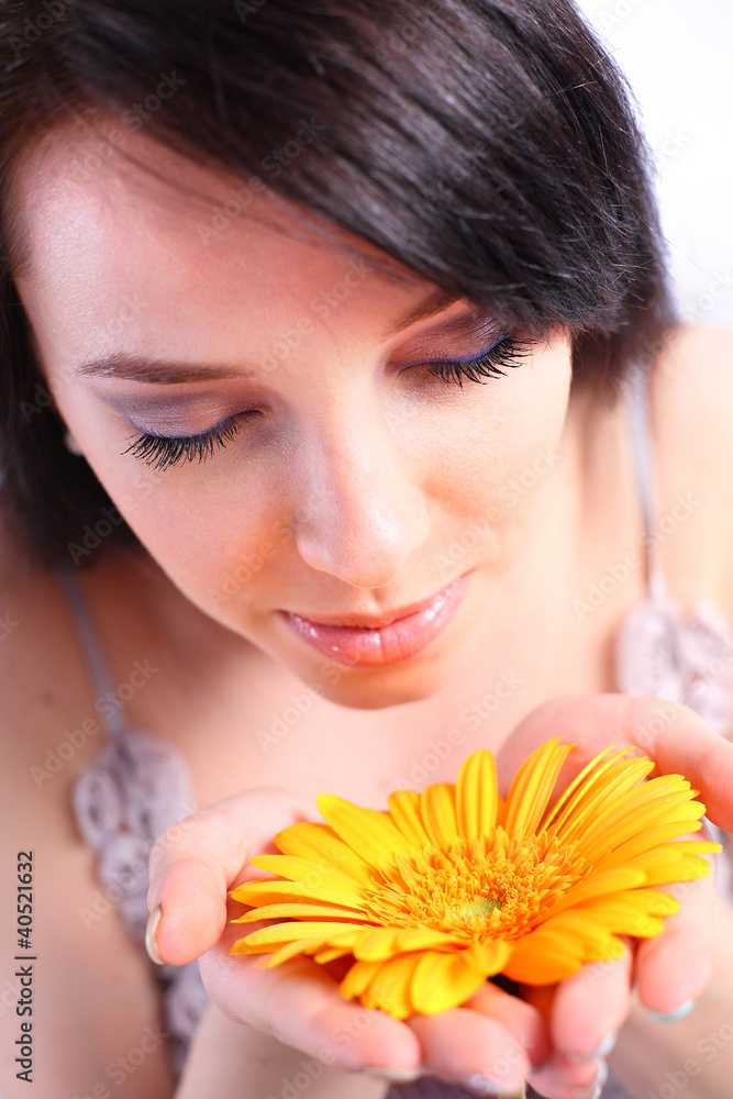 Young woman smelling an orange flower Young woman smelling an orange flower