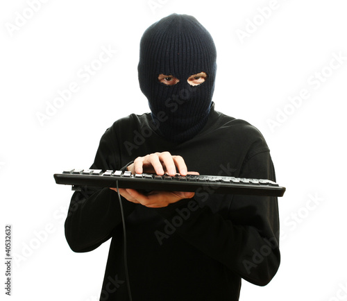 Hacker in black mask with keyboard isolated on white photo