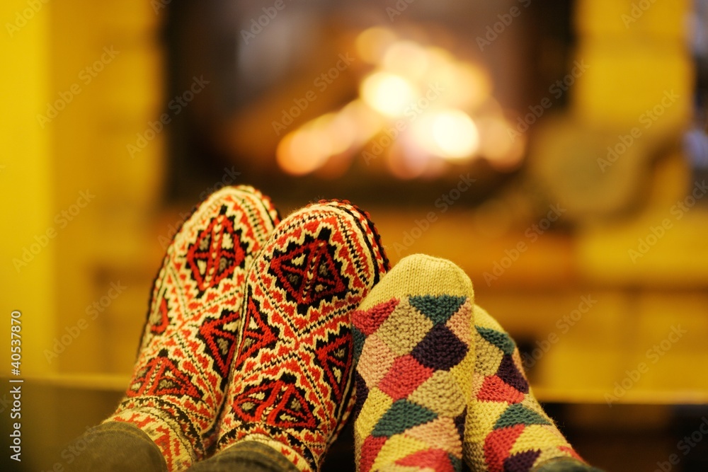 Naklejka Young romantic couple sitting on sofa in front of fireplace at h