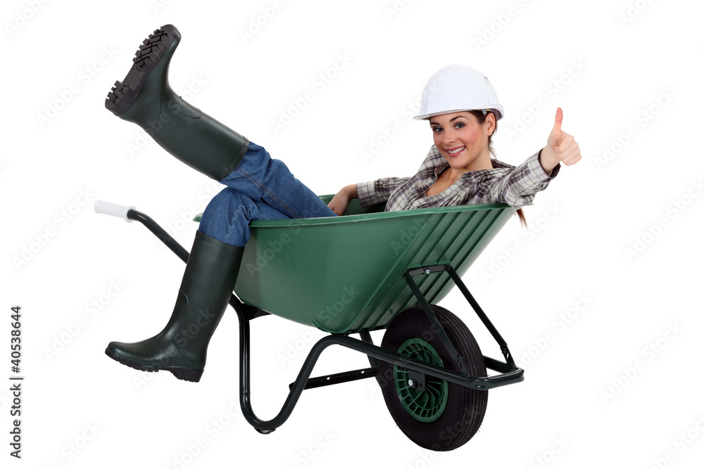 female bricklayer sitting in wheelbarrow thumb up female bricklayer sitting in wheelbarrow thumb up