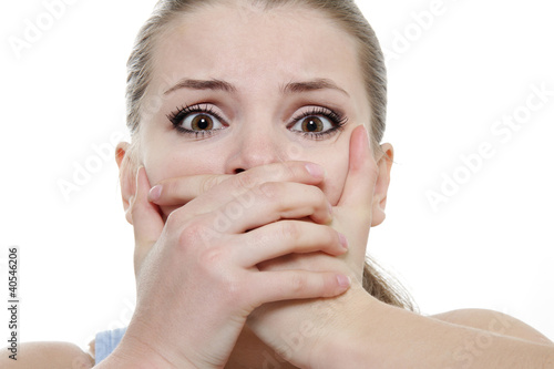 young horrified woman closing her mouth with hands over white