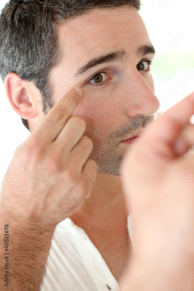 Obraz premium Man in front of mirrror looking at his wrinkles