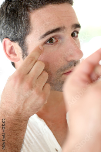 Man in front of mirrror looking at his wrinkles photo