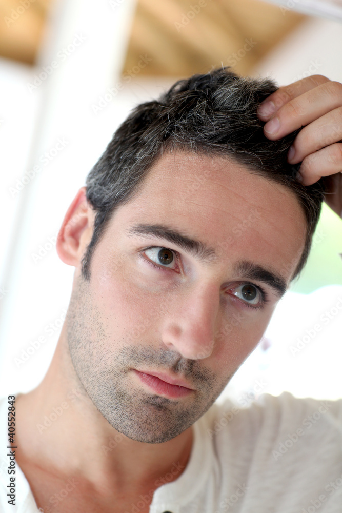 Obraz premium Man in front of mirrror looking at his hair