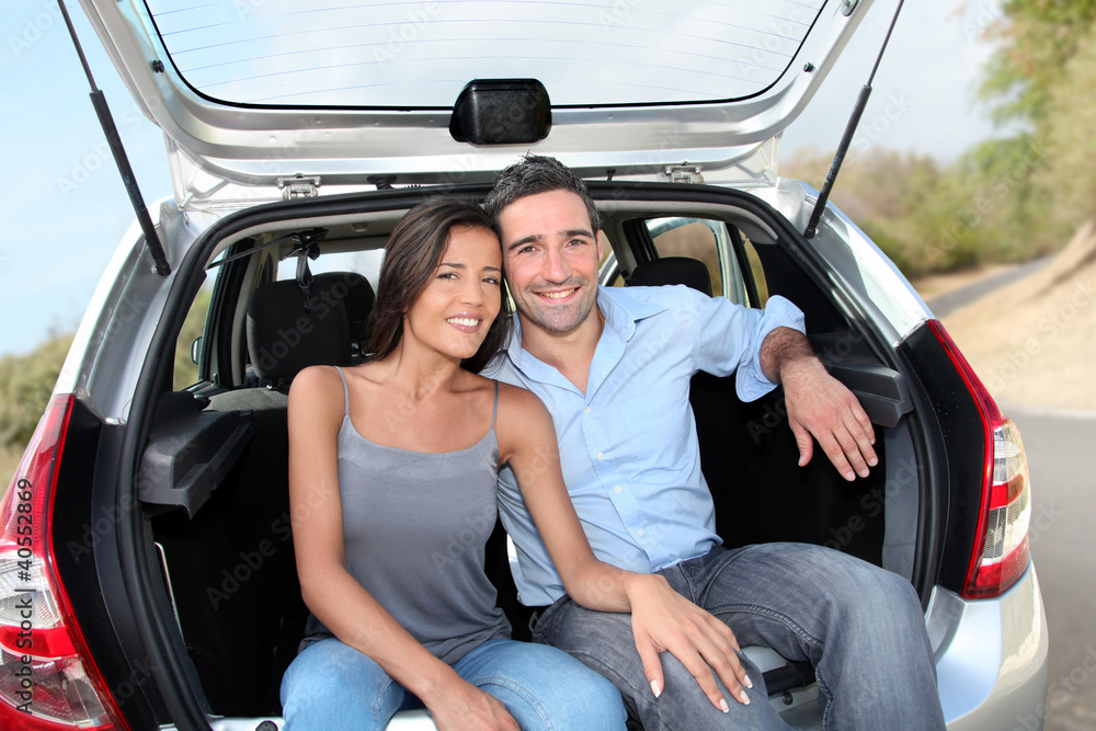 Happy couple sitting in car open trunk Happy couple sitting in car open trunk