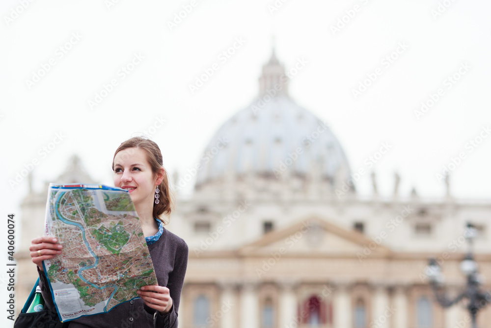 Obraz premium Pretty young female tourist studying a map at St. Peter's square
