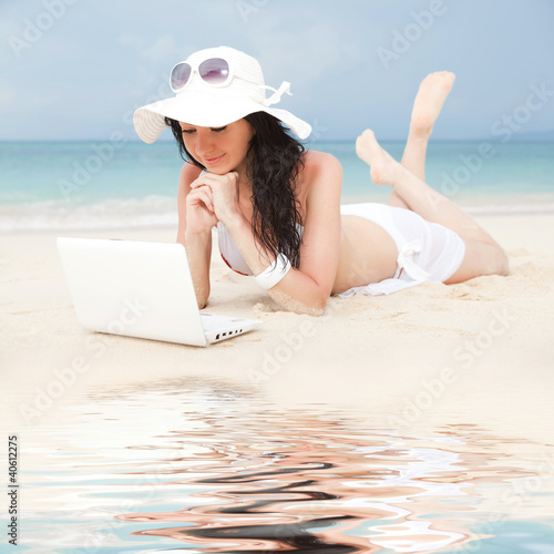 Cute woman with white laptop on the summer beach