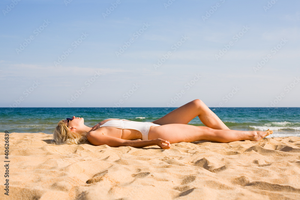 Beautiful blonde girl lying on sand