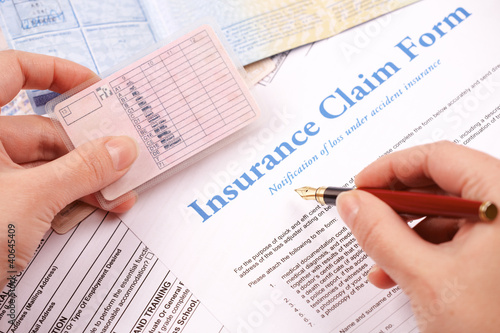 hand filling in insurance claim form