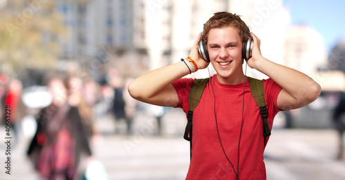 portrait of cheerful young student listening music with headphon