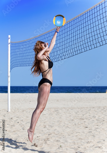 Attractive woman plays in beach volleyball..
