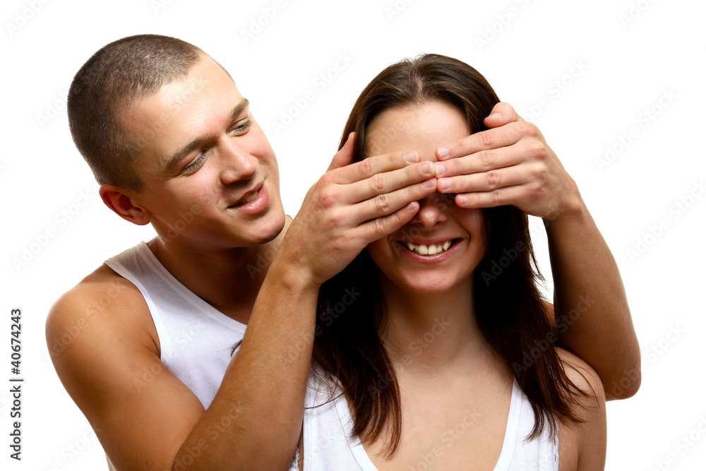 Young man covering his girfriend's eyes with hands isolated Young man covering his girfriend's eyes with hands isolated