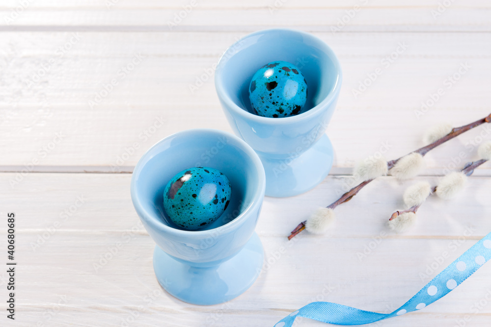 Blue Easter eggs in the glass on the white table Blue Easter eggs in the glass on the white table