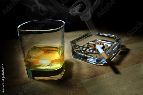 ashtray full of butts and glass of whiskey