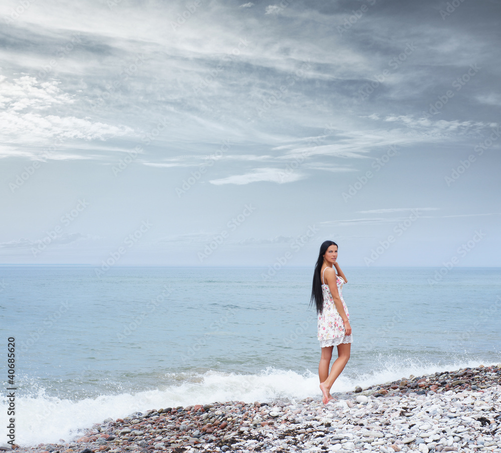 A young brunette woman posing near the blue sea