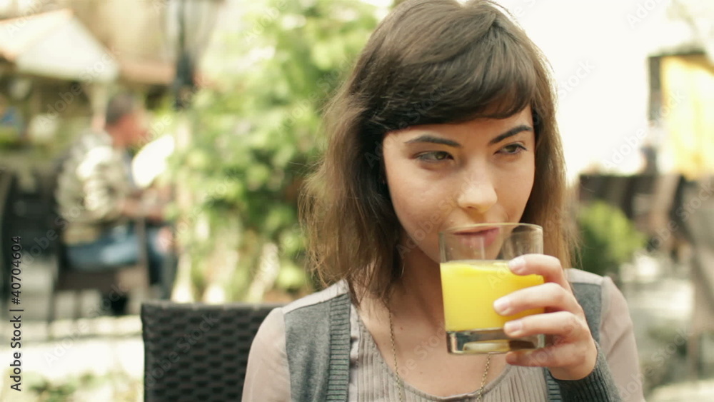 Happy woman drinking juice in outdoor bar, steadicam shot Happy woman drinking juice in outdoor bar, steadicam shot