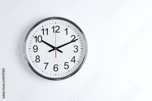 Silver shiny clock hanging at the wall with copy space photo