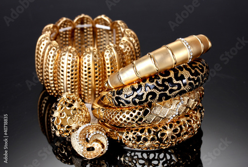 Beautiful golden bracelets and rings on grey background