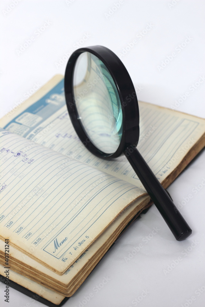 Fototapeta premium Magnifying glass and notebook