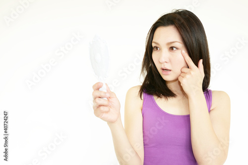シミを気にしている手鏡を持った女性 © sunabesyou