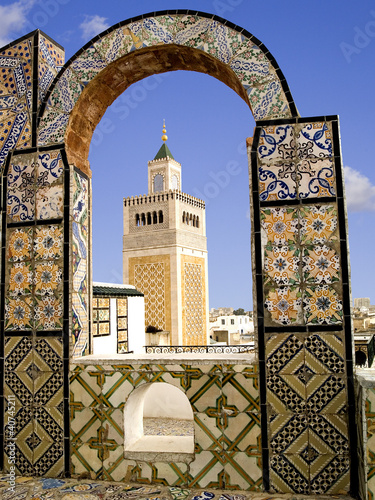 Mosque minaret framed by a tiled arch in Tunis city, Tunisia