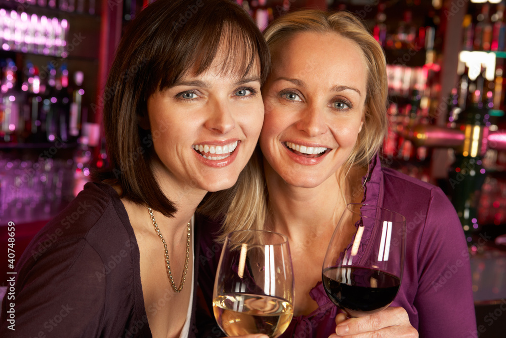 Two Women Enjoying Drink Together In Bar