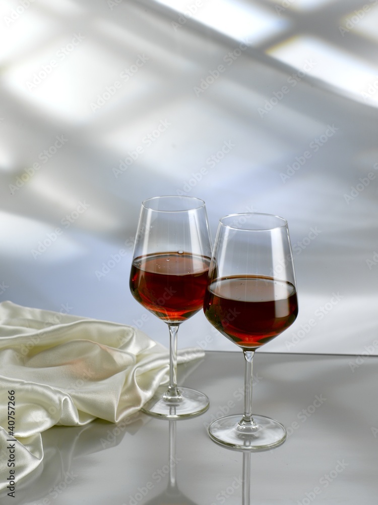 Red wine into two stem glasses on white table Red wine into two stem glasses on white table