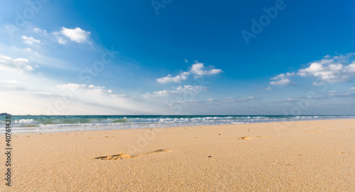 sandy beach with lots of footprints and a blue sky with clouds
