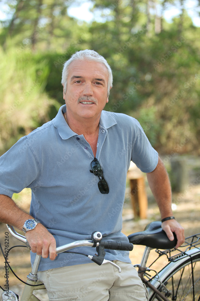 Obraz premium Relaxed senior man leaning on his bike