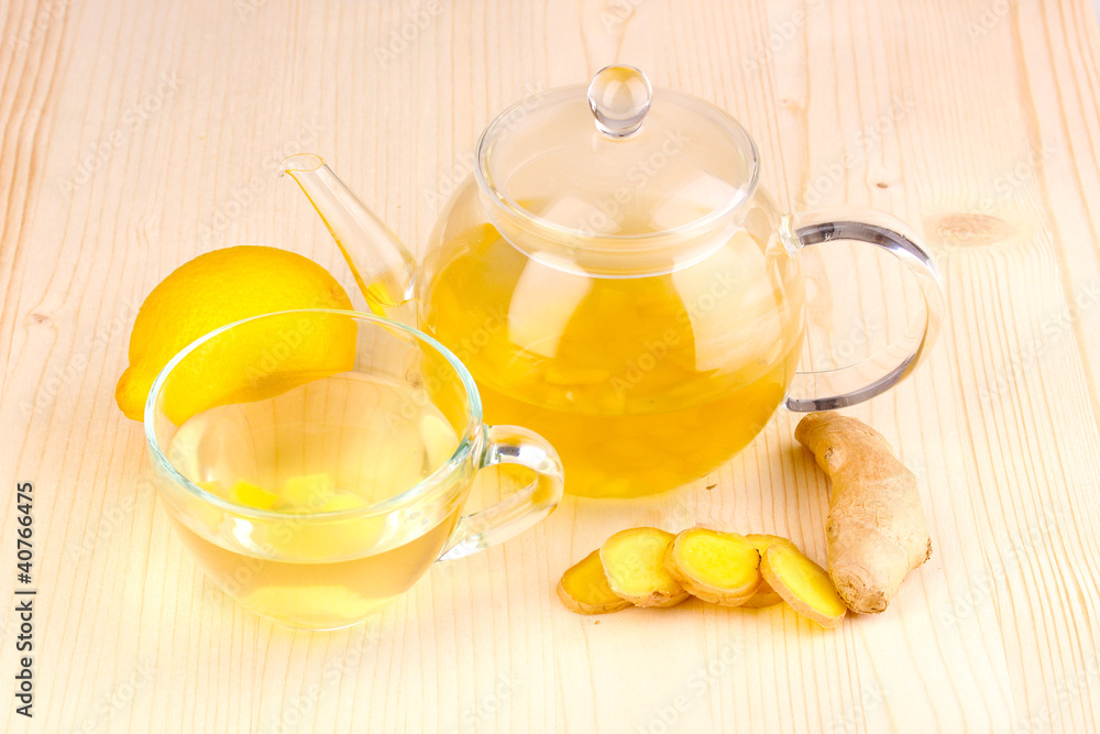 Healthy ginger tea in kettle and cup with lemon Healthy ginger tea in kettle and cup with lemon