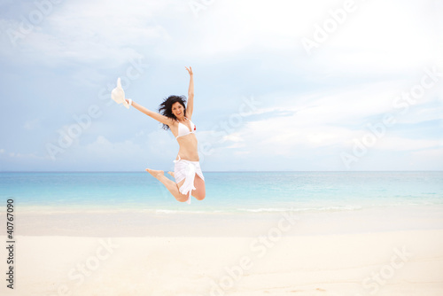 happy young woman jumping on the beach of sea