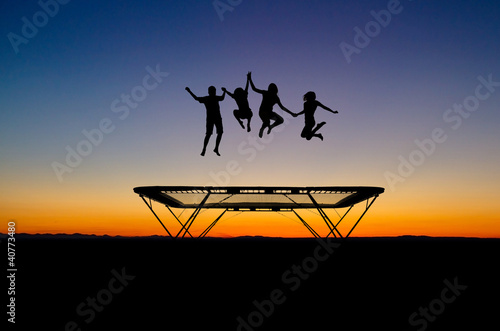 silhouette of kids on trampoline in sunset