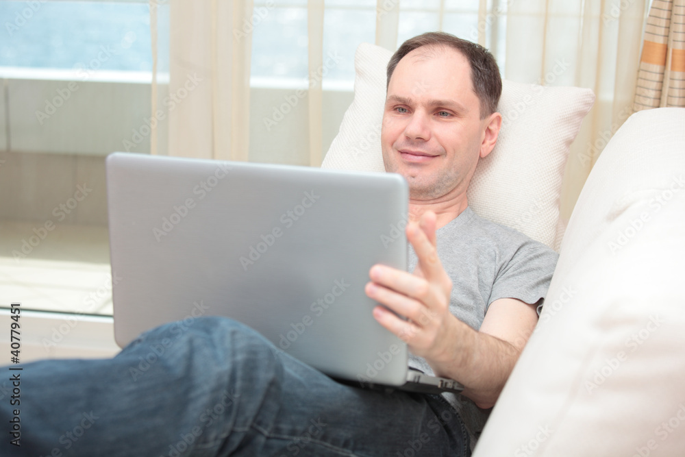 Man with laptop on a sofa Man with laptop on a sofa